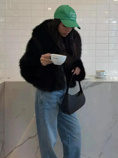 Woman in a green cap and black faux fur coat holding a coffee cup, with jeans 10