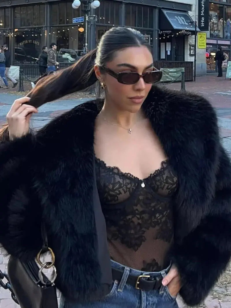 Close-up of a black faux fur coat worn open over a black lace bodysuit and jeans 9