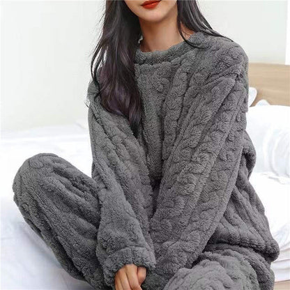 Model sitting on a bed wearing the grey textured fleece pyjama top and matching trousers 4