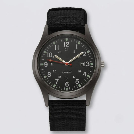 Front view of the watch with a black dial, luminous hands, date window and black woven nylon strap on a plain background. 1