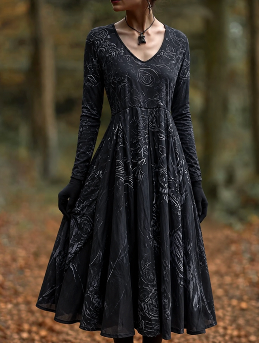 Model in a black long-sleeved V-neck dress with a full flared skirt and swirling rose pattern, standing on an autumn woodland path. 1