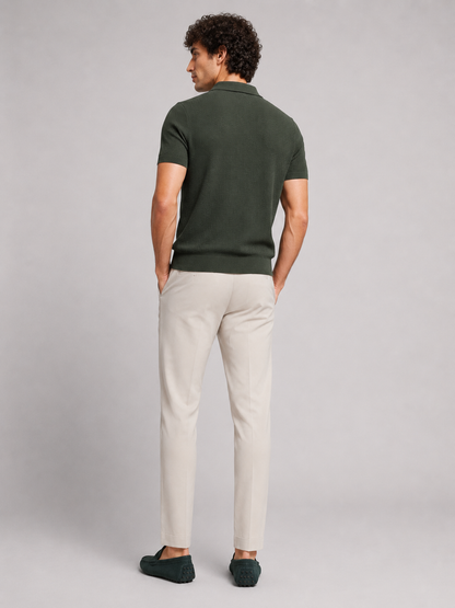 Back view of model wearing dark green knit polo with beige trousers and green driving loafers 14