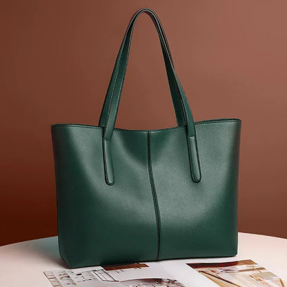 Dark green tote bag angled on a white table against a brown wall, beside a magazine 4