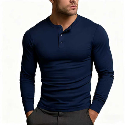 Model wearing the long-sleeve Henley in navy blue, buttons partly undone at the collar, paired with dark grey trousers. 4