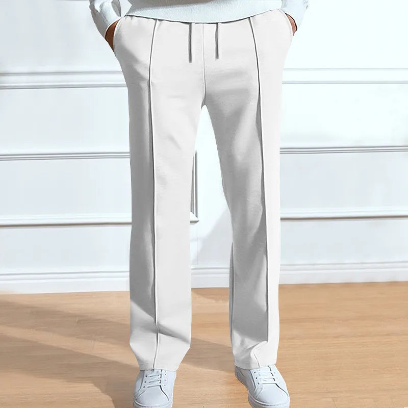 Trousers in white on a model, front view showing the drawstring waist and centre crease lines, worn with white trainers. 4