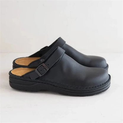 Side view of a pair of black leather clogs with buckle straps, tan footbeds and thick black soles. 4
