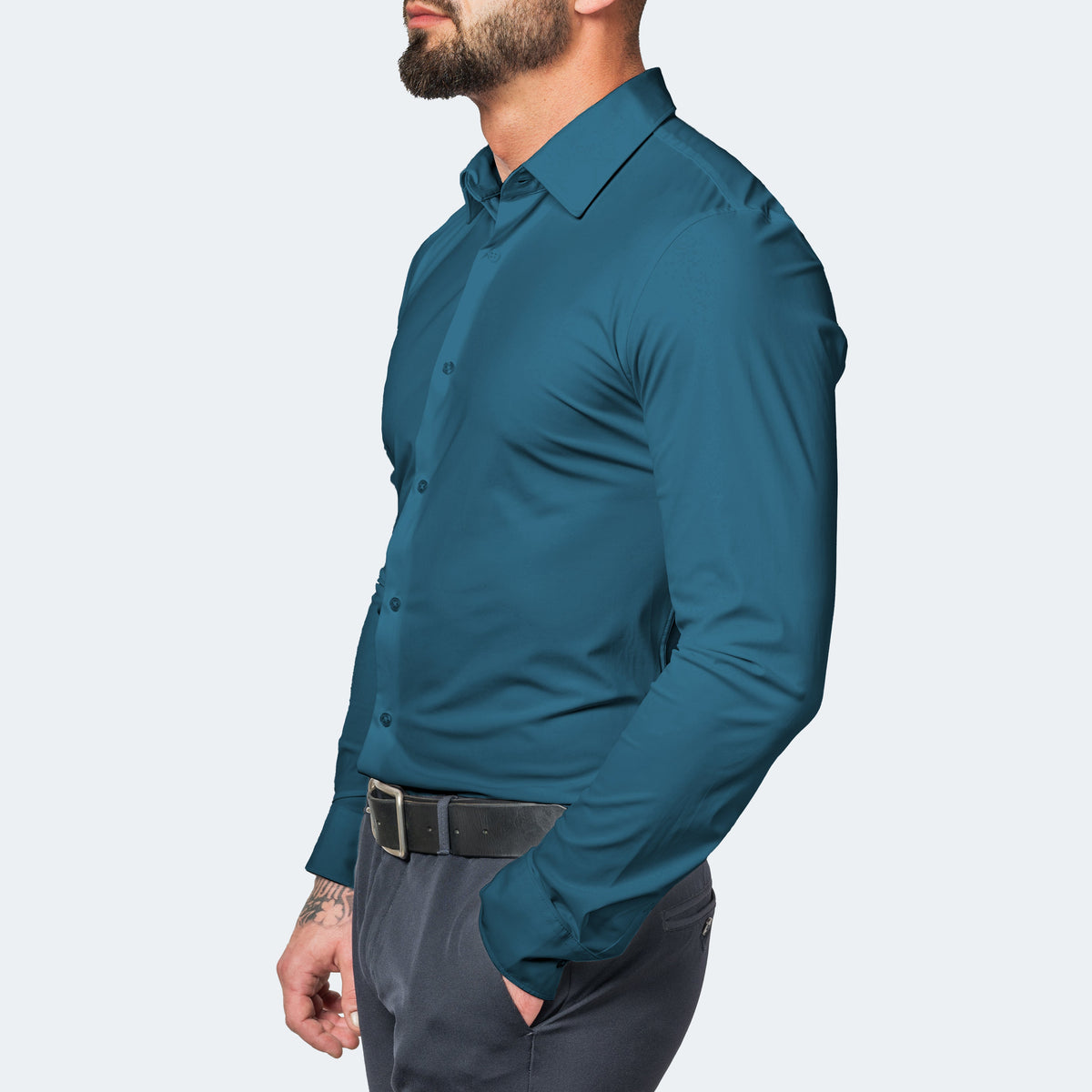 Teal shirt in three-quarter side view, worn with grey trousers, one hand in pocket 11
