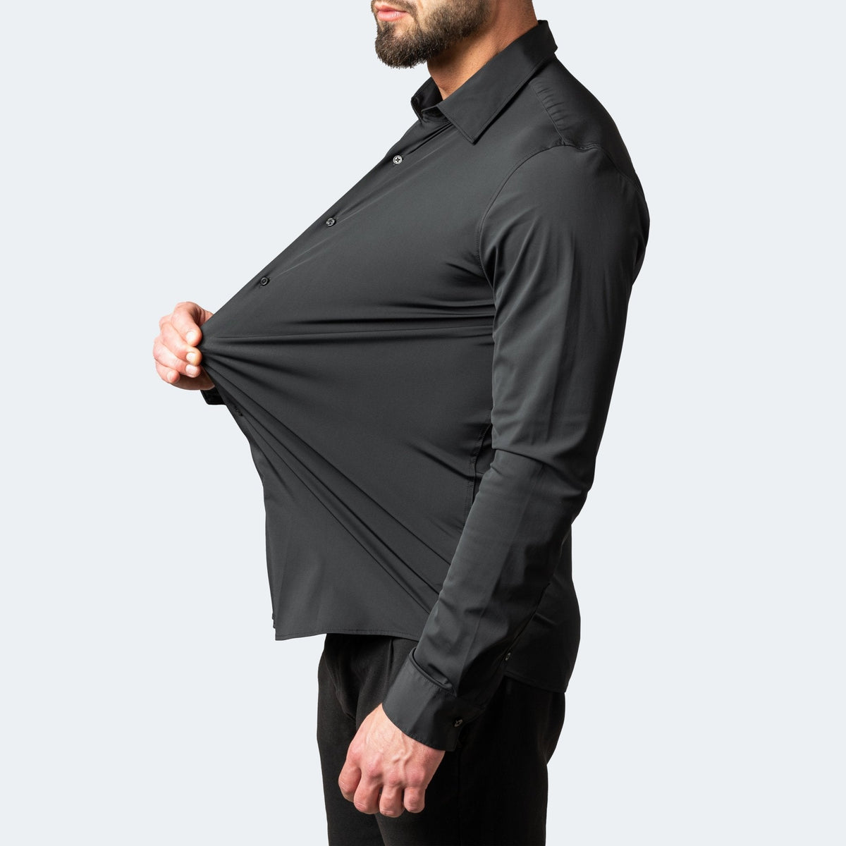 Black shirt in side view, model pinching and pulling the chest fabric forward to show stretch 5
