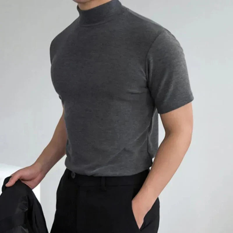 Model wearing the top in charcoal grey, one hand in a pocket and a dark jacket in the other 3