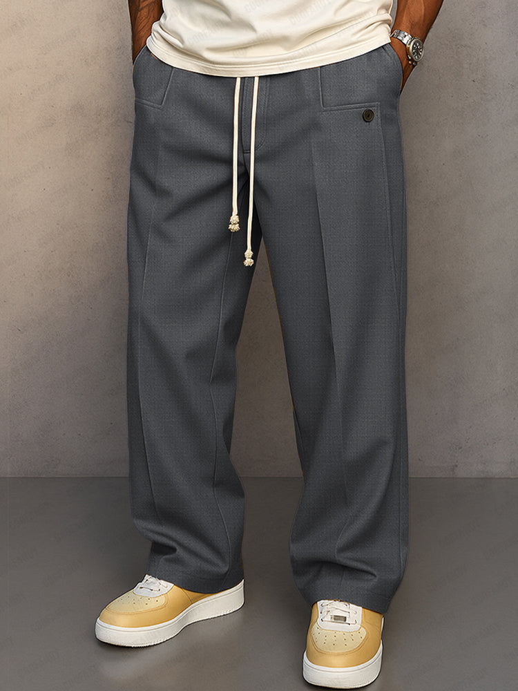 Front view of the wide-leg drawstring trousers in dark grey, styled with a cream t-shirt and yellow trainers. 3