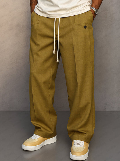 Front view of wide-leg drawstring trousers in mustard olive, worn with a cream t-shirt and cream and yellow trainers. 1