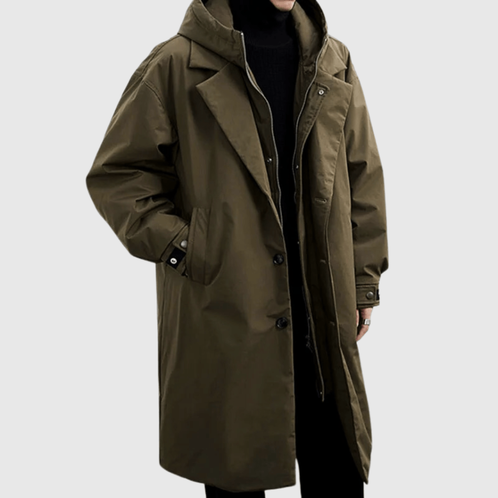 Olive-green long hooded coat worn by a model, three-quarter view, hand in pocket, over black polo neck 1