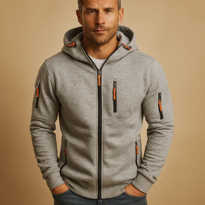 Model wearing the light grey marl hoodie with black zips and orange pulls, showing both zipped sleeve pockets and the hood. 6