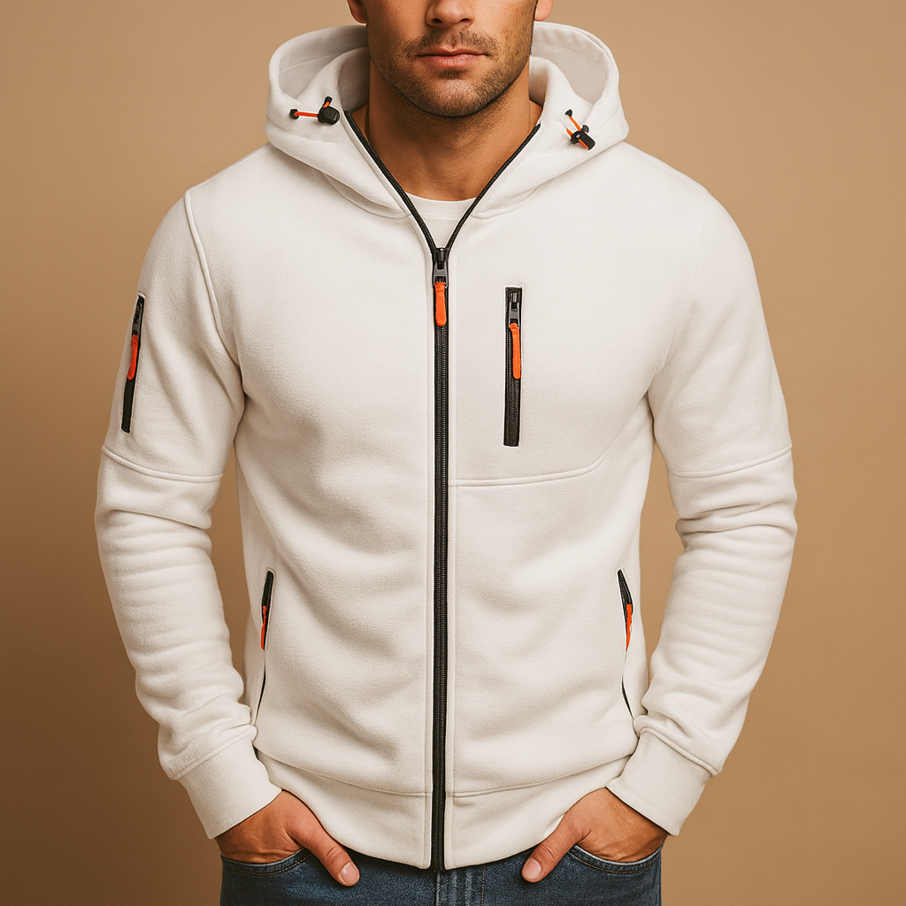 Model with hands in jeans pockets wearing the zipped hoodie in white, with orange zip pulls and toggles on the hood. 1