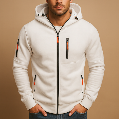 Model with hands in jeans pockets wearing the zipped hoodie in white, with orange zip pulls and toggles on the hood. 1