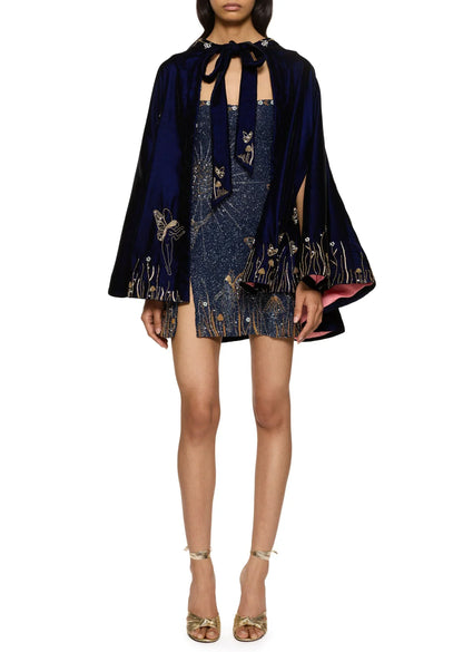 Front view of the dress styled under a navy velvet cape with a tie neck and matching embroidery 9