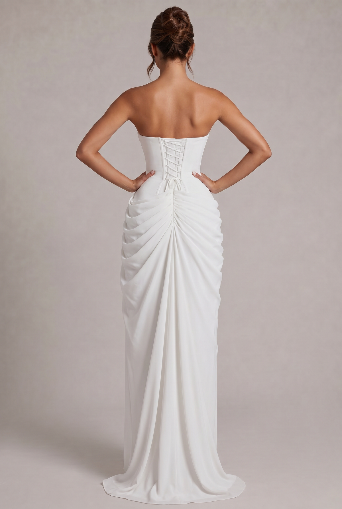 Back view of the white gown with lace-up corset, hair in a bun, gathered train 20