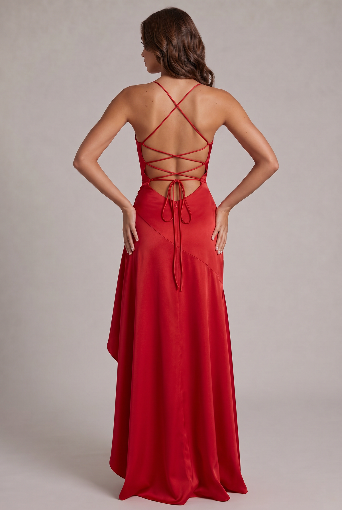 Back of the red satin dress with criss-cross lace-up straps, tie closure and zip, hands on hips 16