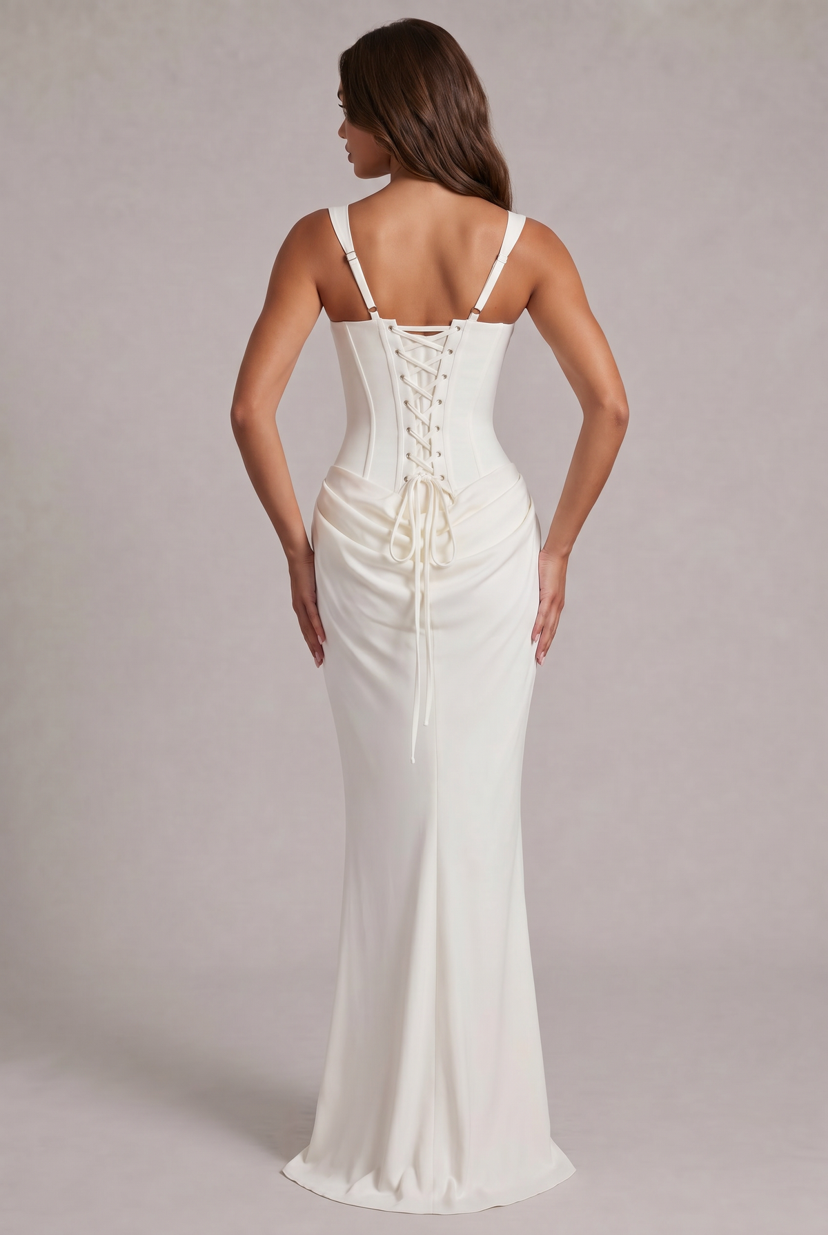 Back view of the white dress, showing the lace-up corset back with eyelets, adjustable straps and trailing laces over the draped skirt. 8