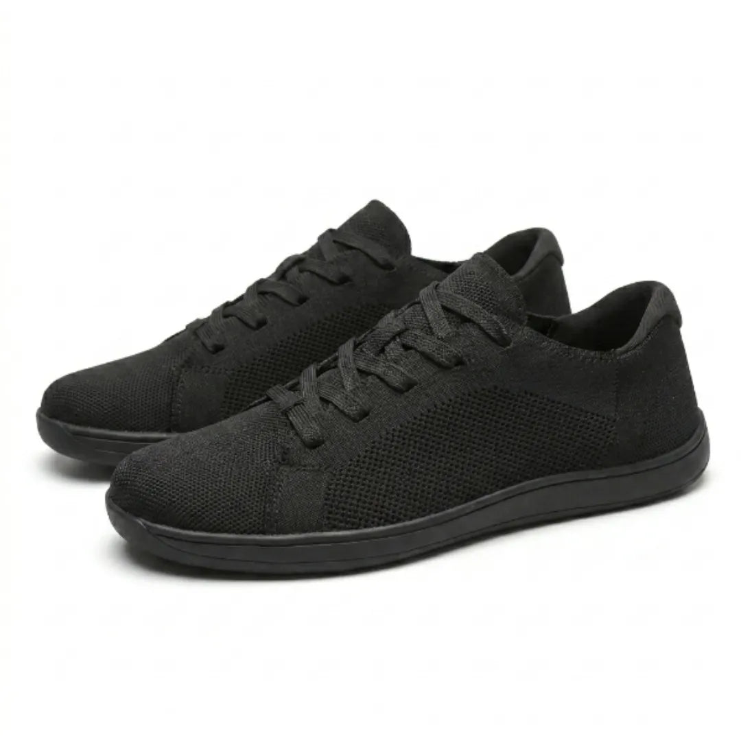 Pair of black knit lace-up trainers at an angle, showing the mesh side panels and the thin flat sole. 16