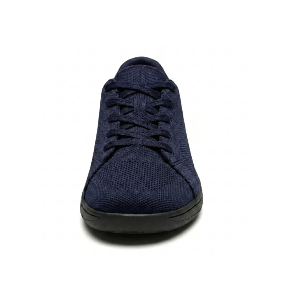 Navy knit trainer seen from the front, showing criss-cross laces, rounded toe cap and flat black sole. 26