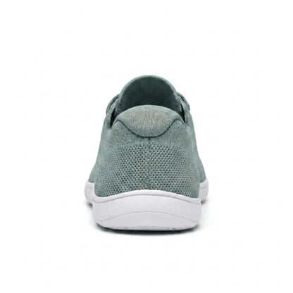 Sage green knit trainer seen from behind, showing the heel tab, textured mesh and flat white sole. 36