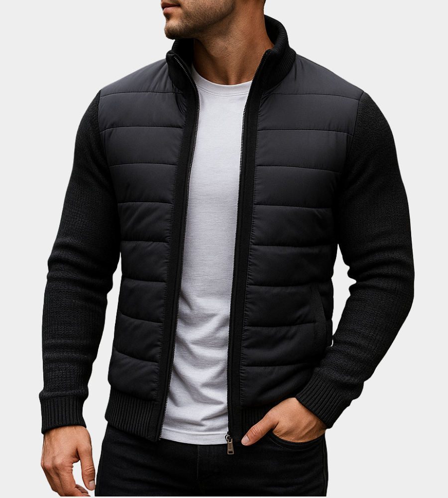 Man wearing the all-black quilted jacket with knitted sleeves and ribbed cuffs, unzipped over a white t-shirt, hand in pocket. 5