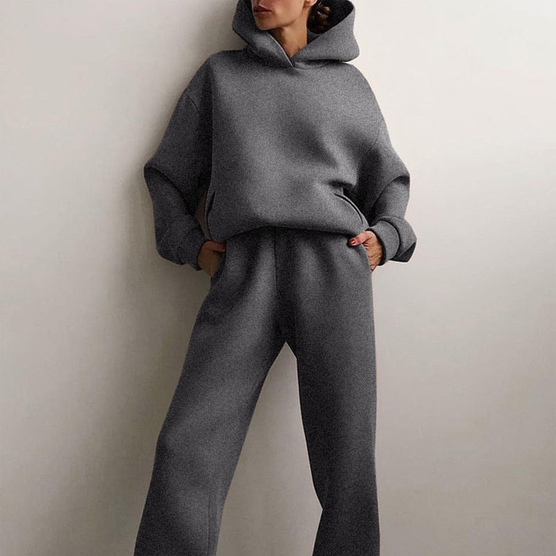 Model standing with hands in the pockets of the dark grey marl hoodie and straight-leg joggers, hood up. 3