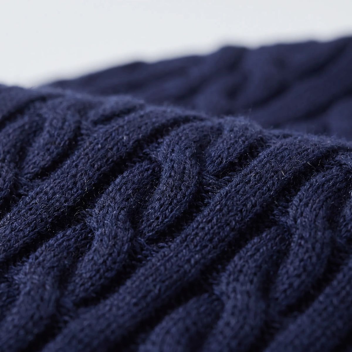 Macro close-up of the navy cable knit texture, showing the twisted cables and soft, slightly fluffy wool-like surface. 9