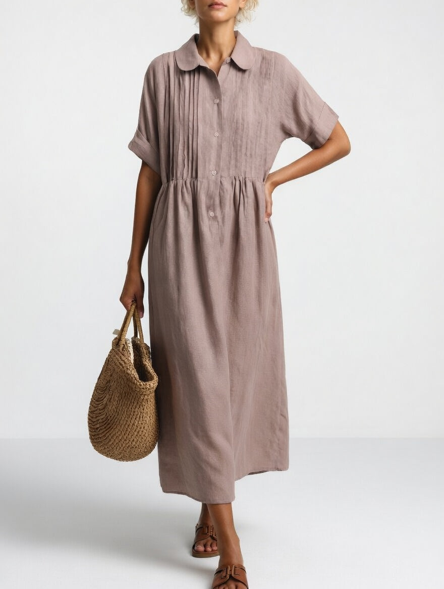 Model in the muted mauve-taupe dress with a hand on her hip, showing pleated bodice, buttons and gathered skirt. 8