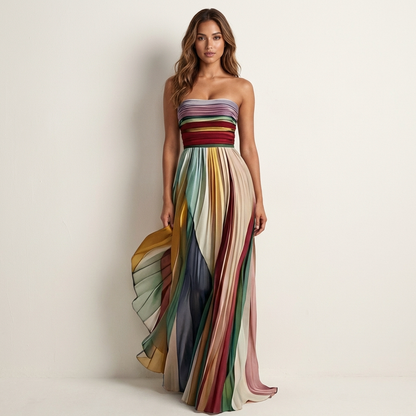 Model in a strapless striped pleated maxi dress with a ruched bodice, standing front-on as one side of the skirt flares out. 1