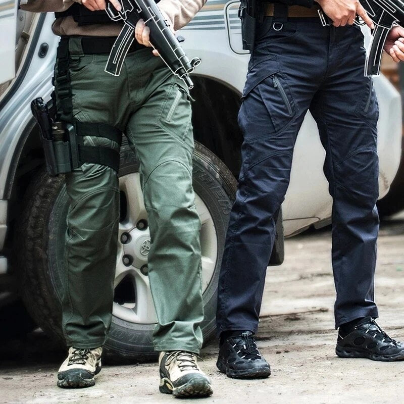 Two men standing beside a parked vehicle, one in olive green and one in navy trousers with zipped thigh pockets. 2
