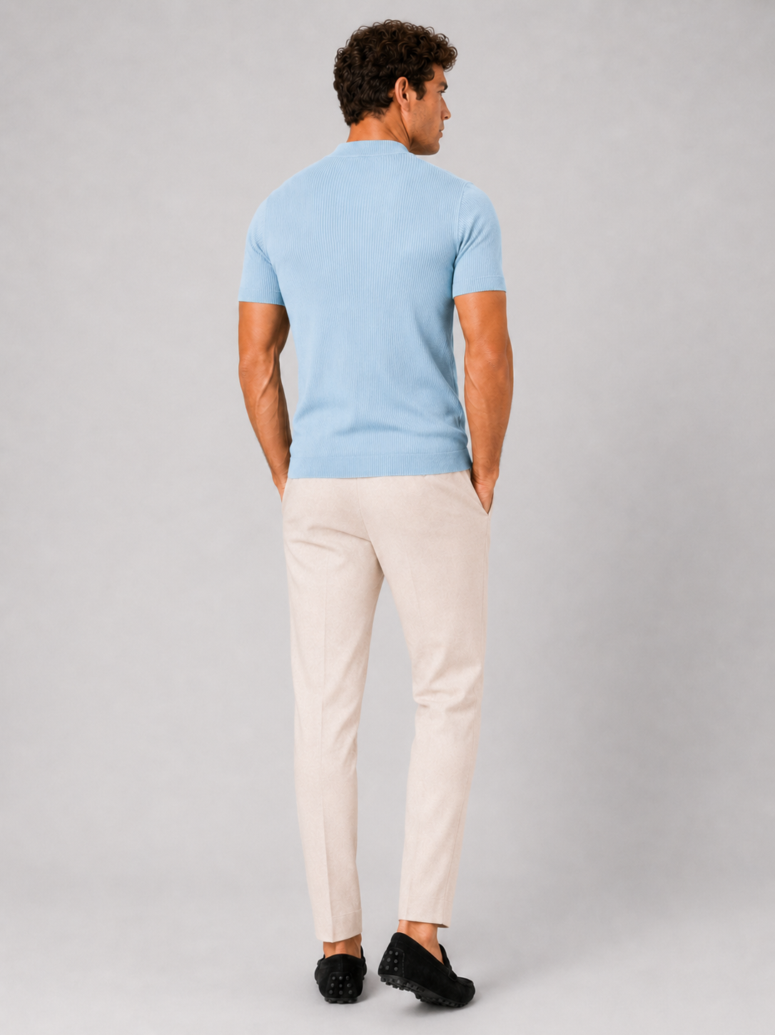 Back view of the light blue ribbed top worn with cream trousers and black loafers. 10