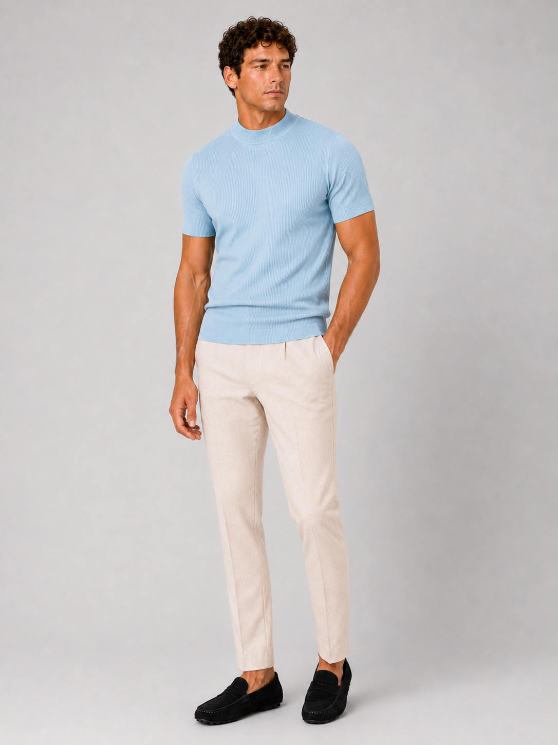 Full-length studio shot of the light blue top with cream trousers and black suede loafers. 9