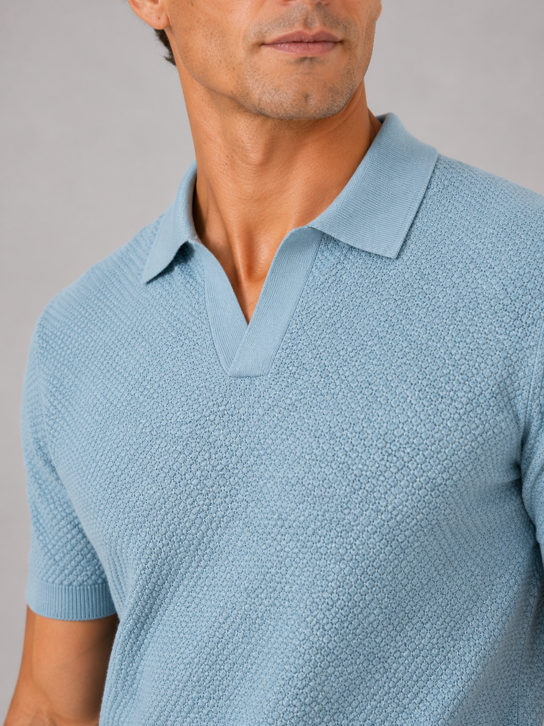 Close-up of light blue polo's open collar, honeycomb knit texture and ribbed sleeve cuff 2