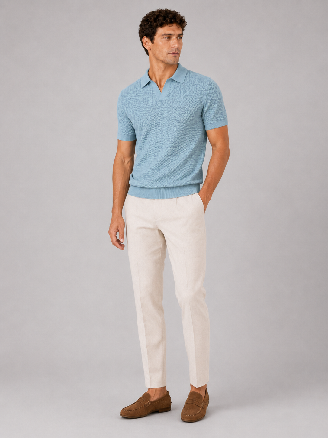 Full-length front view of model in light blue knit polo, cream trousers and brown suede loafers 3