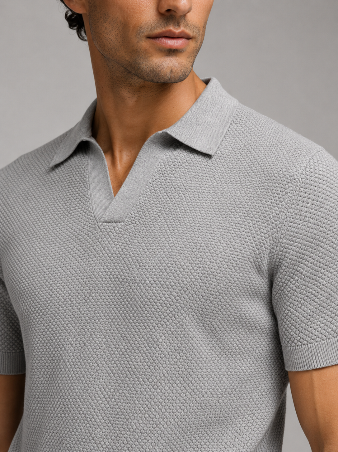 Close-up of grey knit polo showing the honeycomb texture, open V-neck collar and ribbed short sleeve cuff 27
