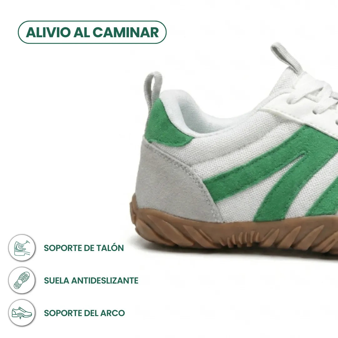 Close-up of the heel of the white shoe with green suede stripes and grey heel patch, with icons for heel, grip and arch support. 31