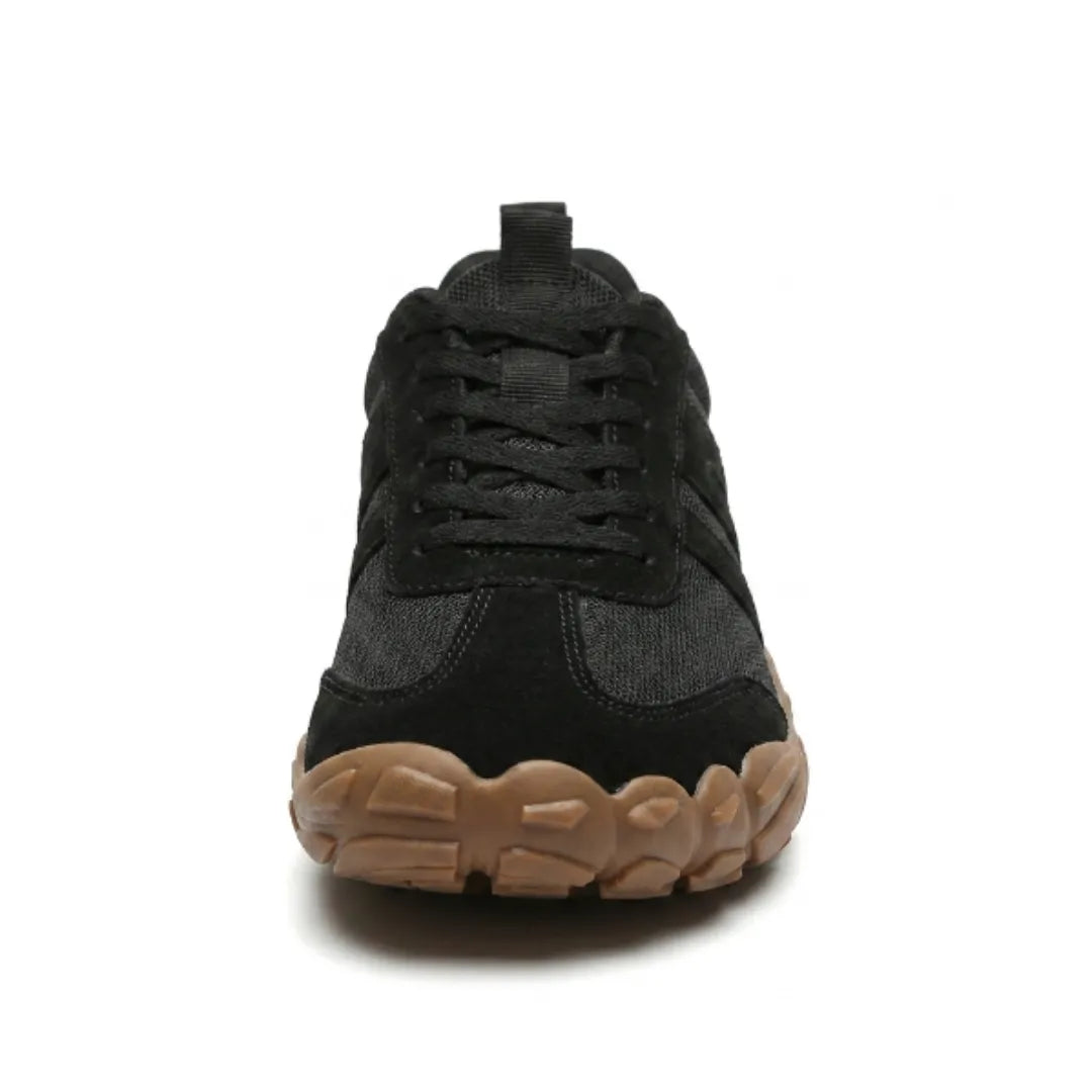 Front view of the black lace-up shoe showing the broad, rounded toe and tan sole with scalloped tread. 26