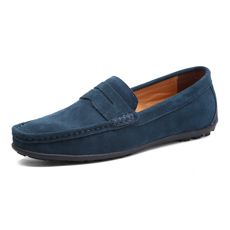 Slate blue suede penny loafer shown from the front three-quarter angle, with stitched moccasin toe and tan lining. 2