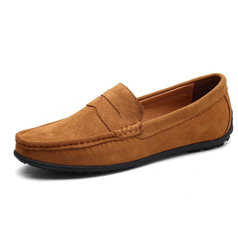 Tan suede penny loafer in front three-quarter view, showing the saddle strap, hand-stitched toe and black studded sole. 3