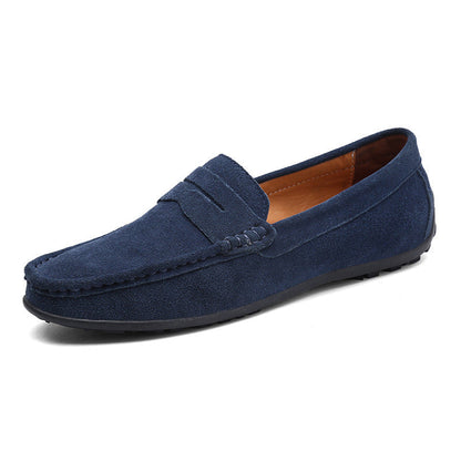 Navy suede penny loafer in front three-quarter view, showing the penny strap, tan lining and low black rubber sole. 7