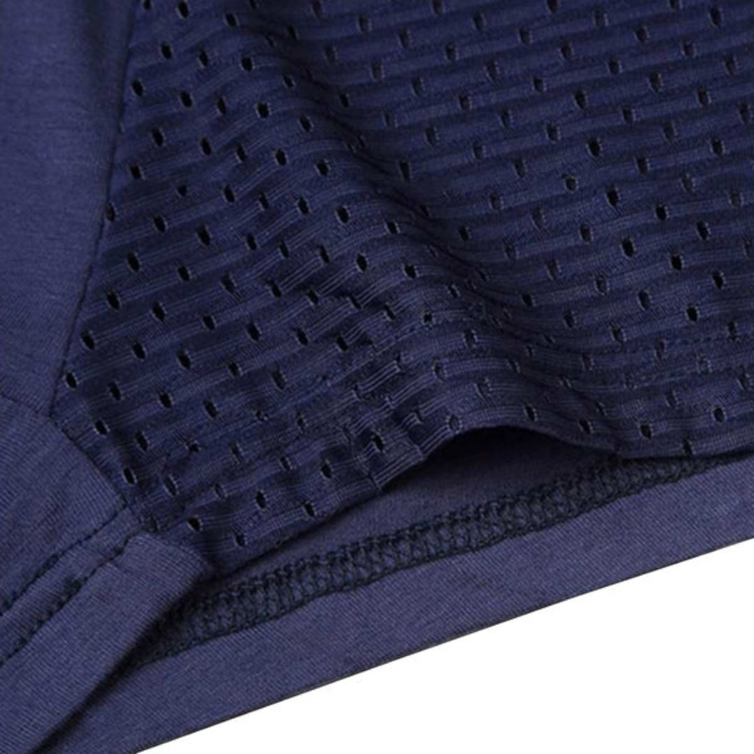 Close-up of navy boxer briefs at the leg opening, showing the perforated mesh panel, stitched hem and smooth fabric beside it. 11