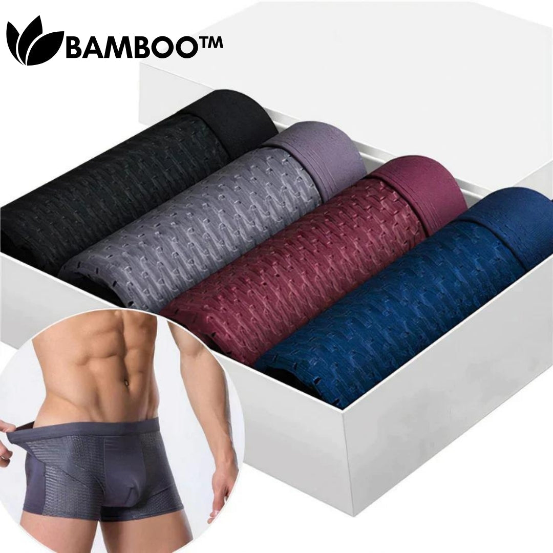 Four rolled boxer briefs in black, grey, burgundy and navy lined up in a white box, with a small inset of a model pulling the waistband. 2