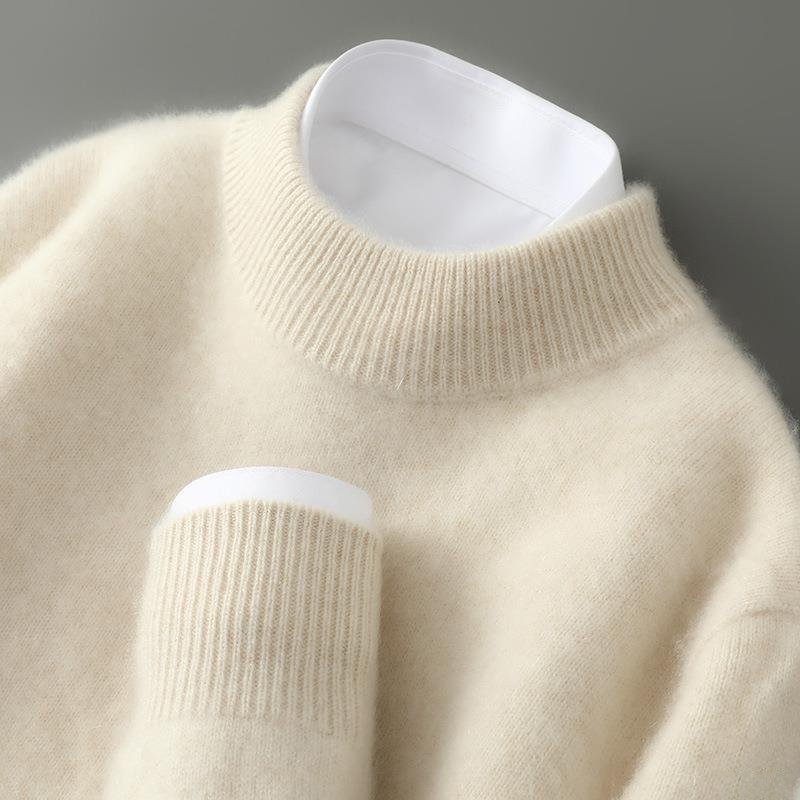 Close-up of the ribbed mock neck and cuff of a soft cream knit jumper, with a white shirt collar showing. 1