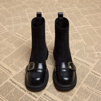 Front view of the black suede ankle boots side by side, showing the glossy leather toe caps and brass buckle straps. 5