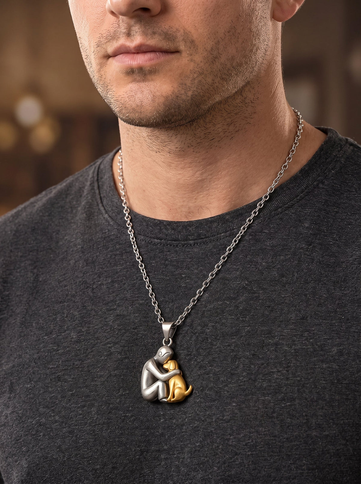 Man in a dark grey t-shirt wearing the matt silver and gold-toned dog pendant on a longer chain 11