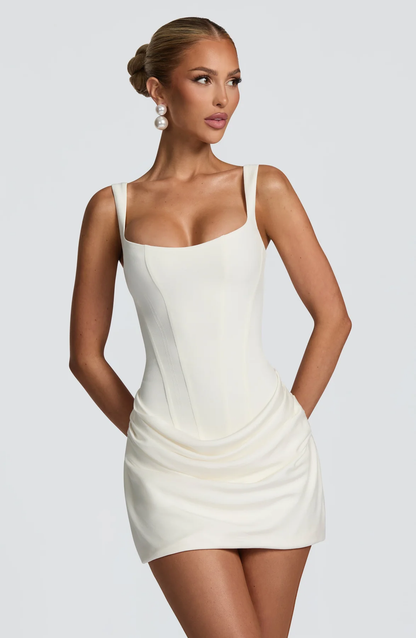 Close front view of the cream dress on a model, showing the seamed corset bodice, wide straps and draped skirt. 1