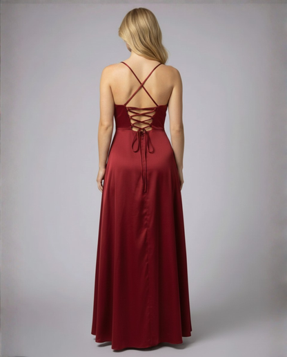 Back view of the model in the burgundy satin dress, showing crossed straps, a lace-up corset back and a long flowing skirt. 3