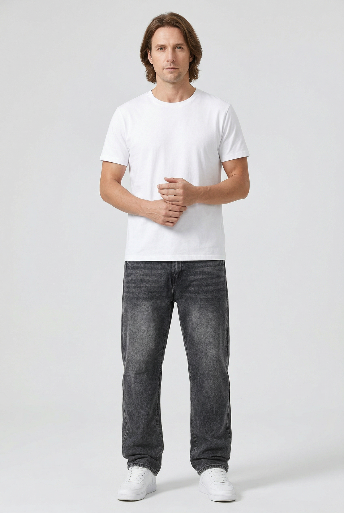 Full-length front view of a man wearing the washed grey jeans with a white tee and trainers 2